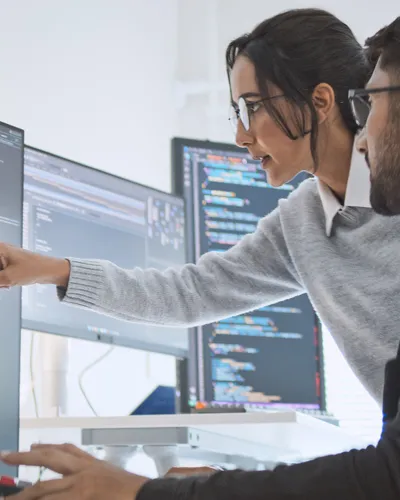 Data Strategy 2 Kollegen schauen sich an mehreren Bildschirmen Code an